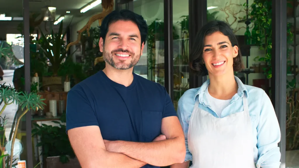 Two small business owners standing in front of their shop