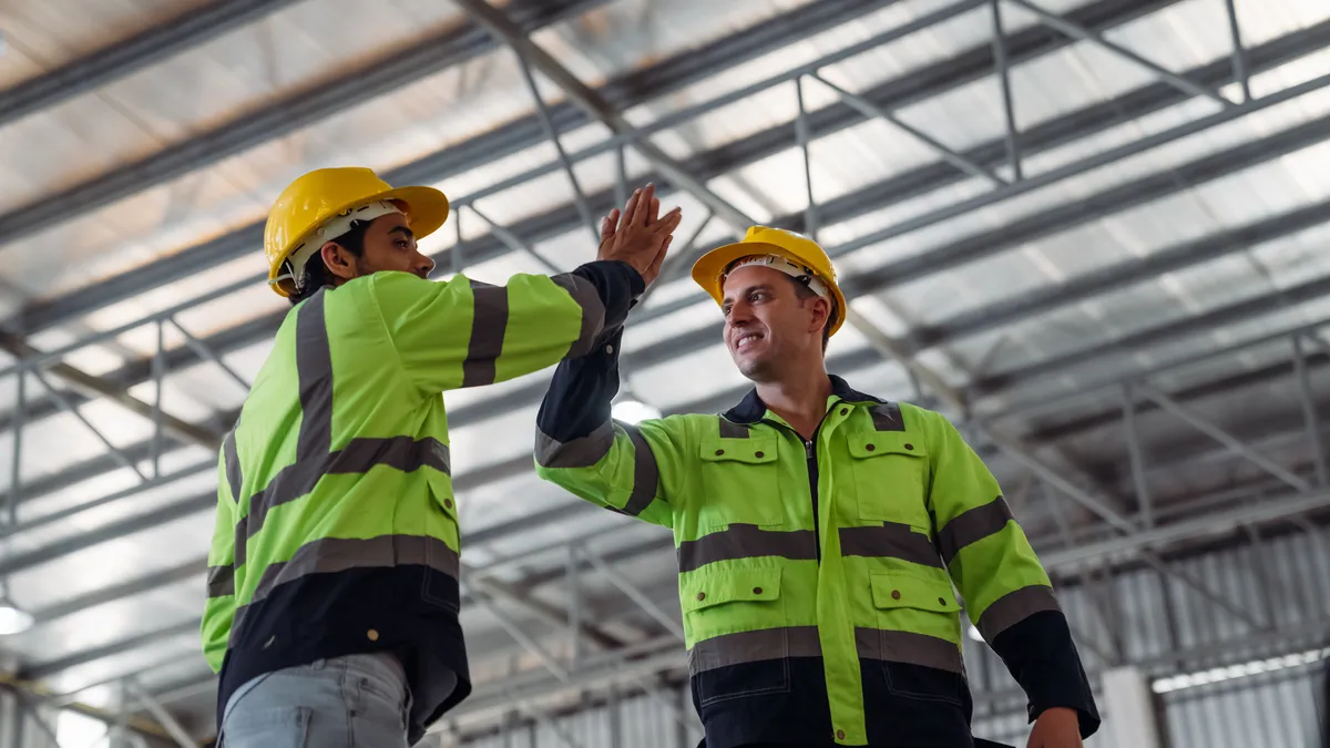 Two tradies in hi-vis workwear discussing a job on a construction site
